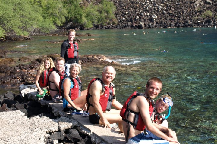 Jane Bunnett et al. sitting on a rock next to a body of water