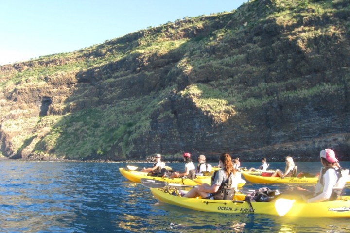 a group of people riding on the back of a boat in the water